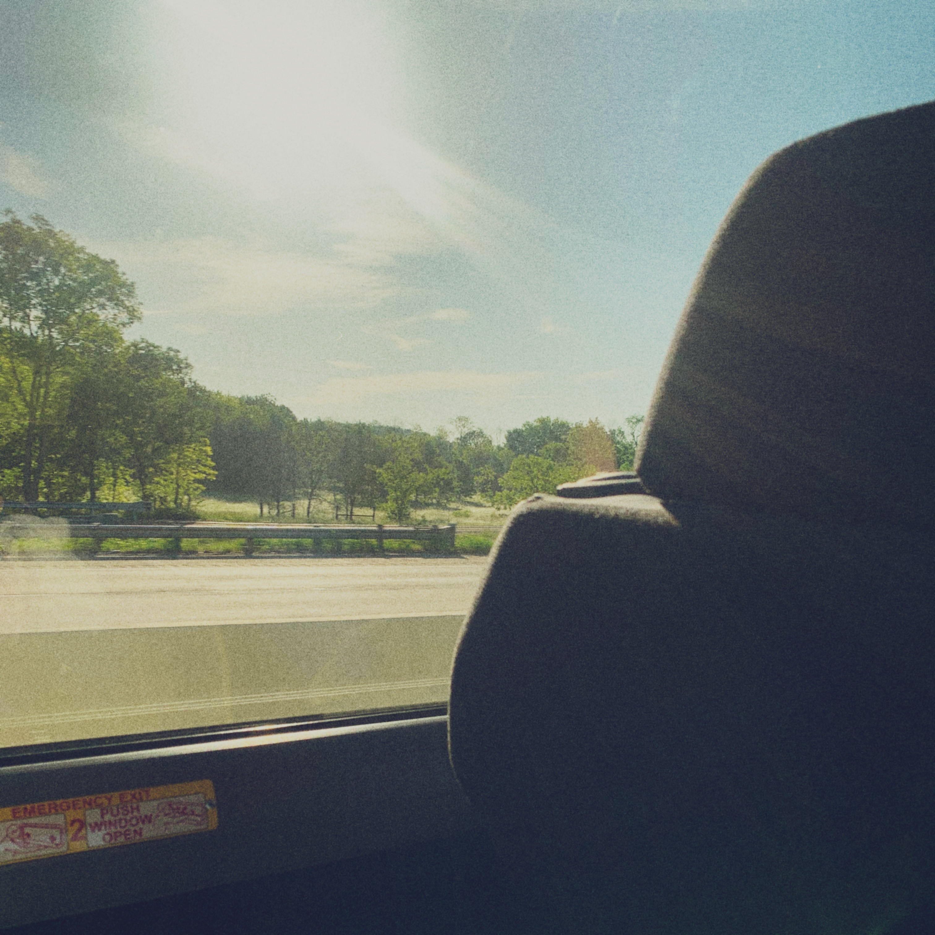 This is a picture of a window and i'm inside a bus with the sun blinding me.